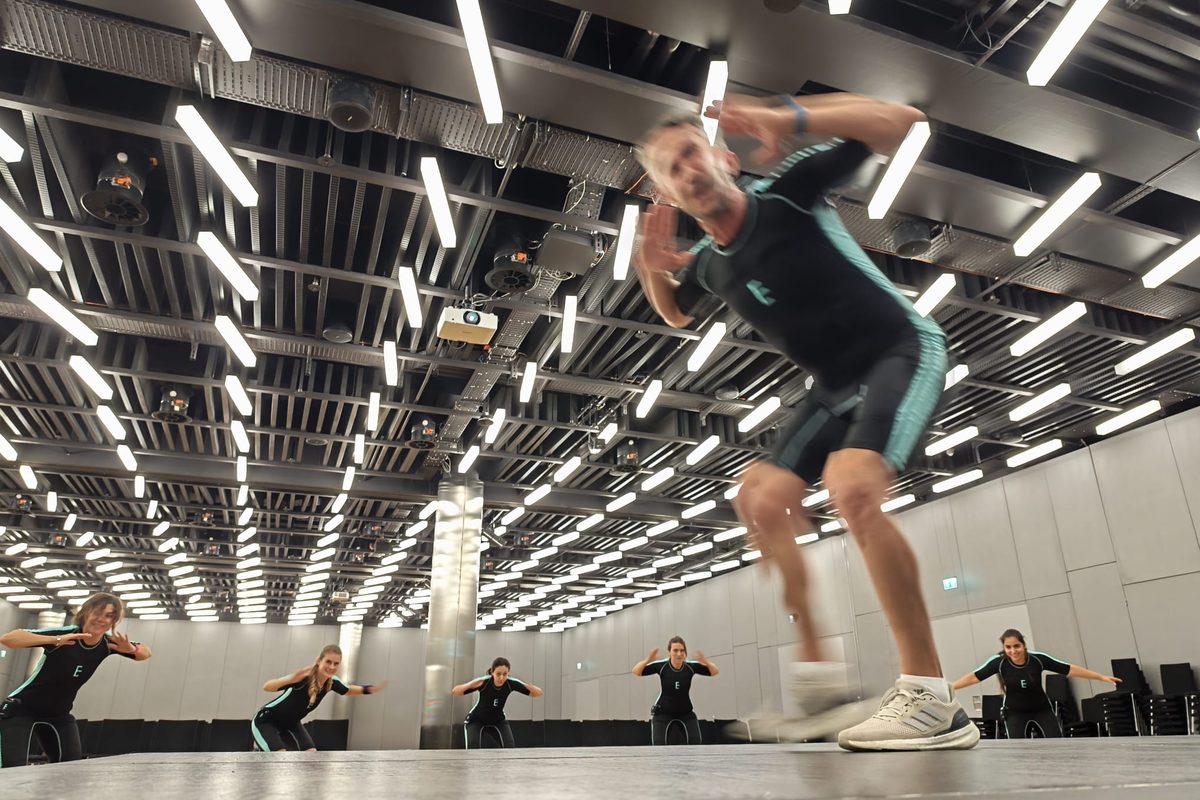 Séance EMS collectif — coach en plein mouvement devant le groupe